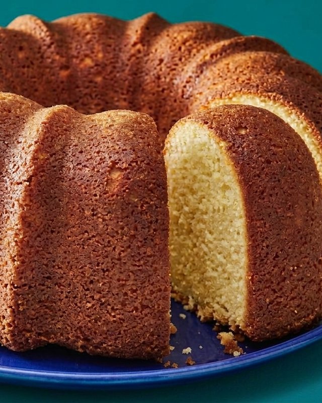Golden 5-flavor Bundt pound cake with a slice cut out, on a blue plate